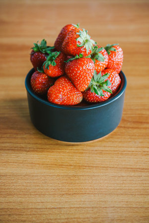 Strawberries in a bowl on a wooden table. Selective focus.の写真素材