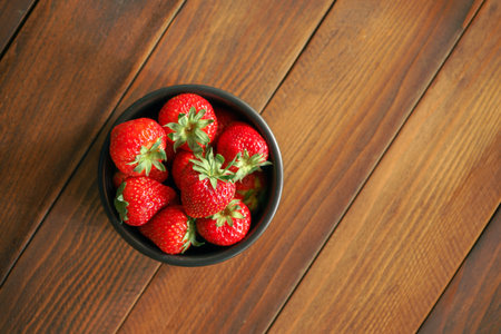 Strawberries in a bowl on a wooden background, top viewの写真素材