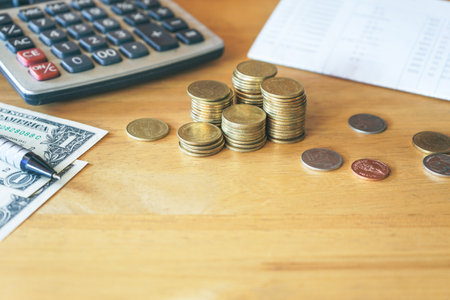 Coins and calculator on the wooden table, business and finance conceptの写真素材
