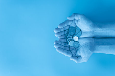 Coins in a woman's hands on a blue background, top viewの写真素材