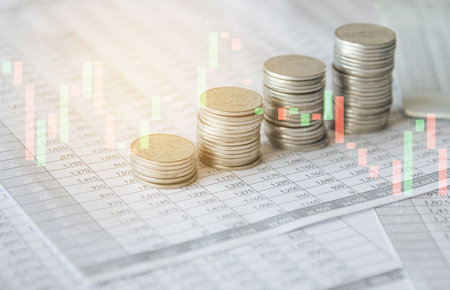 Coins stacked on each other on the background of a financial chart.の写真素材