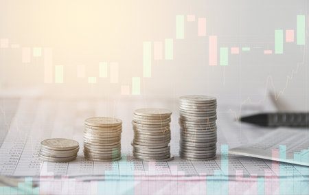 Stacks of coins with stock market graph background, business and finance conceptの写真素材