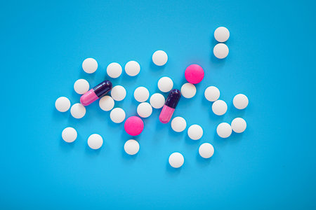 White and pink pills on blue background. Top view, flat layの写真素材
