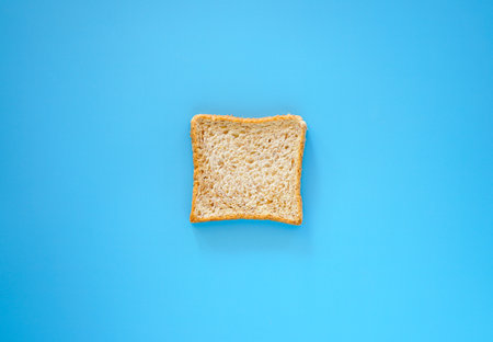 Slice of toast bread on blue background, top view, copy spaceの写真素材