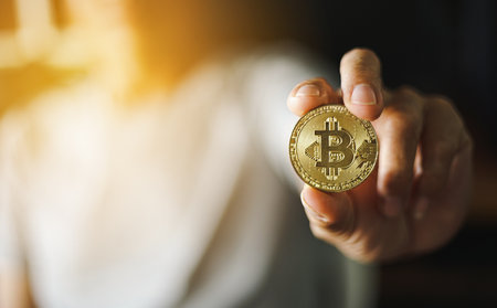 Golden bitcoin in the hand of a business man. Cryptocurrency concept.の写真素材