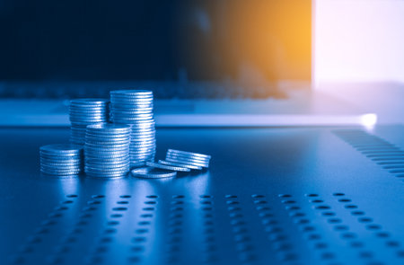Coins stacked on each other with laptop computer background, business and finance concept.の写真素材