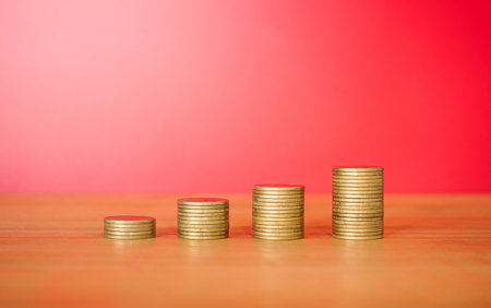 Stacks of coins on wooden table and red background, business conceptの写真素材
