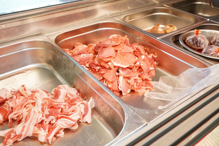 Slices of raw pork in stainless steel trays at the supermarketの写真素材