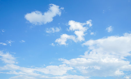 Blue sky background with white clouds, soft focus, and copy space.の写真素材