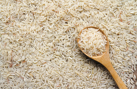 Rice in wooden spoon on wooden background. Close-up.の写真素材