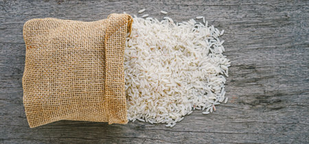 Rice in burlap bag on wooden background, top view.の写真素材