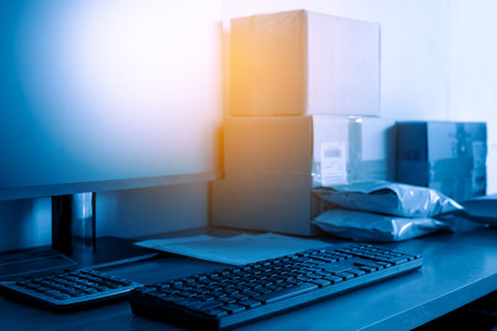 Close up of a computer with boxes on the desk in the officeの写真素材