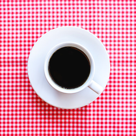 Coffee cup on red and white checkered tableclothの写真素材