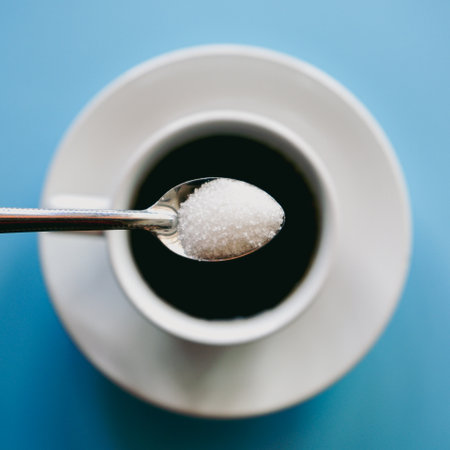 Sugar in a spoon and a cup of coffee on a blue backgroundの写真素材