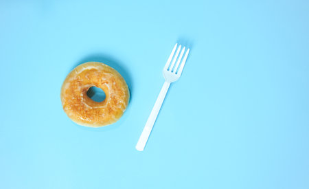 Donut and fork on blue background. Top view with copy space.の写真素材