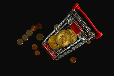 Shopping cart with golden bitcoin and coins isolated on black background.の写真素材
