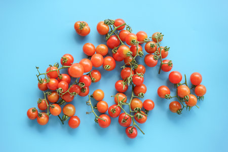 Bunch of fresh cherry tomatoes on blue background. Top view.