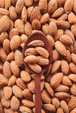 Almonds in wooden spoon on the background of the almond huskの写真素材