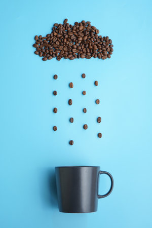 Coffee beans arrange like rainy clouds and a cup of coffee on a blue backgroundの写真素材