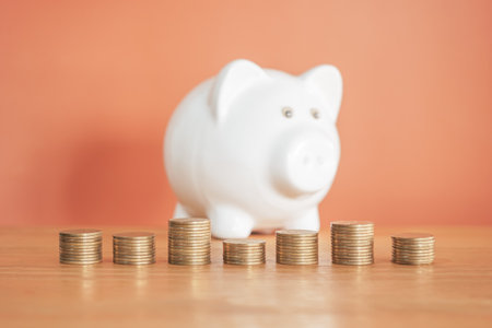 Piggy bank with coin stack on wooden table and red backgroundの写真素材