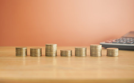 Coins stacked on each other with calculator in the background, business and finance concept