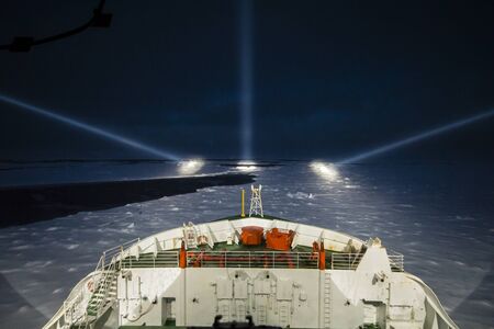 Icebreaker ship cruising at night by the aid of night-piercing projectors in the polar seaの写真素材