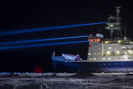 Icebreaker research vessel near a research site marked with safety flags searching by strong projectorsの写真素材