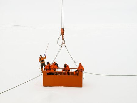 Scientists checking the integrity and thickness of an ice floe from a basket lowered from the...