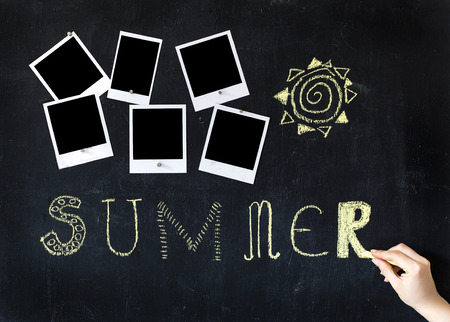 Woman writing on a metal blackboard with chalk and six blank retro photo frames attached with small magnetsの写真素材