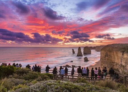 Twelve Apostles, Great Ocean Road, Australia â April 18, 2019: People looking at the stunning sunset at Twelve Apostles, limestone pinnacles formed by erosion of the cliffs by Southern Ocean, a popular touristic destination at Great Ocean Road.のeditorial素材