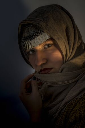 Portrait of a young girl with a scarf and coin jewelry on her head and hand holding his scarf as a symbol of her chastity.の写真素材