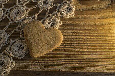 Cookie with shape of heart on knitted tablecloth and wooden tableの写真素材