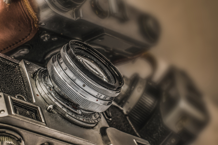 Close up view of old Russian analog film camera with vintage look. On the camera, there can be seen aperture ring, focusing ring, lens, filter thread. In background is another old camera with lensの写真素材