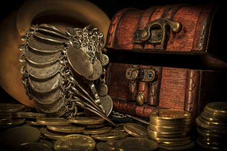 Treasure chest, pile and pillar of coins, and a ceramic bowl filled with jewelry coins in dark environmentの写真素材