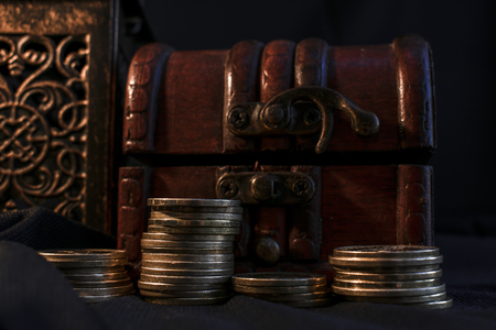 Treasure chest, pillar of coins and candle lamp in dark environmentの写真素材