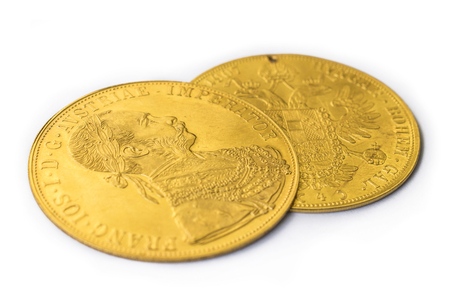Close-up view in perspective of two on one another Austria-Hungary thalers, avers and revers of golden coin-ducats from 1915 with Kaiser Franz Joseph I, on white backgroundの写真素材