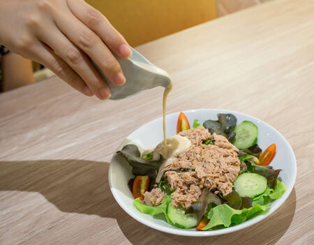 Pour sauce on tuna salad in bowlの写真素材