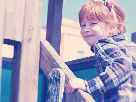 five-six-year-old little girl with red hair on the playground turning towards the viewer and smilingの写真素材