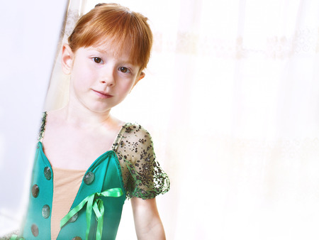 Little redheaded girl wearing green trimmed costume of ballet dancer for a performanceの写真素材