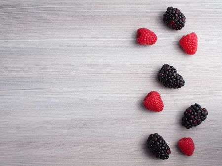 Blackberries and raspberries on grey wooden backgroundの写真素材
