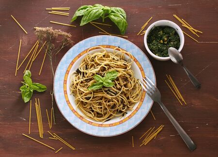Italian spaghetti with pesto sauce on dark brown wooden backgroundの写真素材