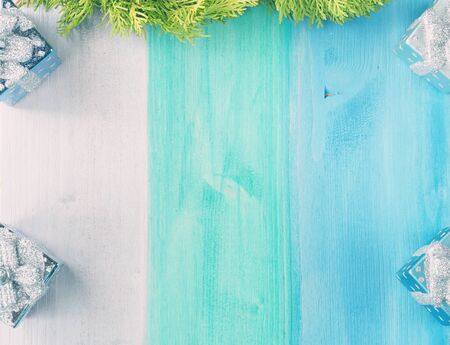 Wooden silver, green and blue pastel background with christmas tree decorations on the sides and thuja branch on the top, top view, copy spaceの写真素材