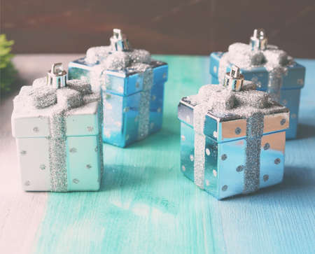 Christmas still life with christmas tree decorations with shape of small gifts on green and blue pastel wooden backgroundの写真素材
