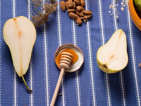 Pears, honey and almonds for breakfast on blue table clothの写真素材