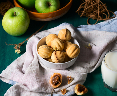 Still life on green wooden table with sandy pastry cookies, milk and applesの写真素材