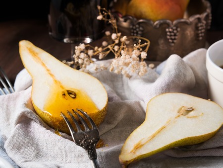 Pears on a napkin on rustic wooden table with wine and honey aroundの写真素材