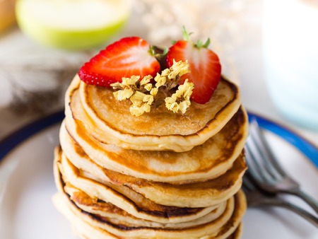 Breakfast with stacked yogurt pancakes with strawberries on beige table clothの写真素材