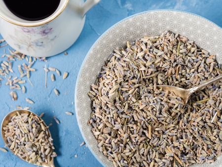Lavender flowers in a bowl and lavender syrup on blue textured backgroundの写真素材