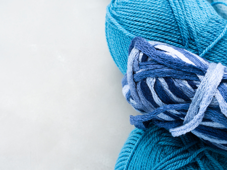 Winter color wool yarn with knitting needles. Blue palette and gray clews. Gray background with...