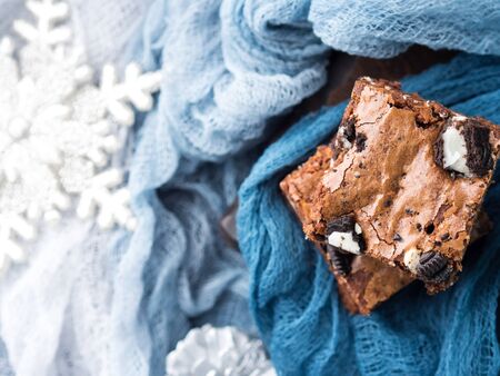 Cream cheese brownies with cookies on blue. Winter christmas treat square chocolate bars.の写真素材